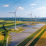 Landschaft mit Windrädern und Solarenergieflächen.