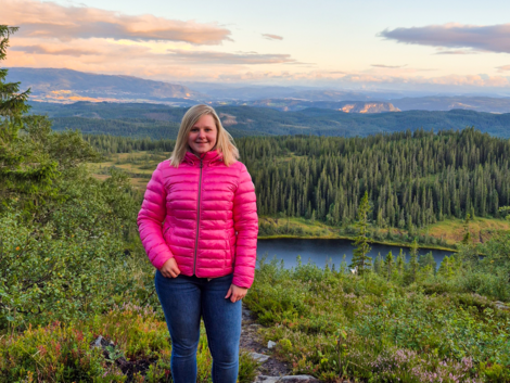 Das Bild zeigt Studentin Sophie vor einer grünen Landschaft in Norwegen.